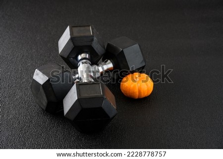 Fall harvest fitness, mini orange pumpkin with a pair of traditional hex dumbbells
