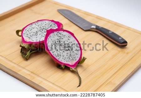 Cut red dragon fruit on a board. Cut in two pieces with a sharp knife