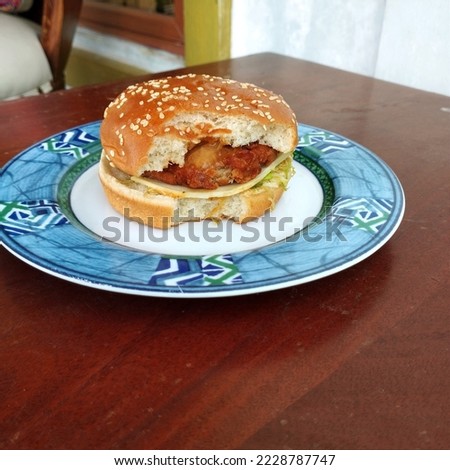 bitten fast food hamburger
on a plate with a wooden background