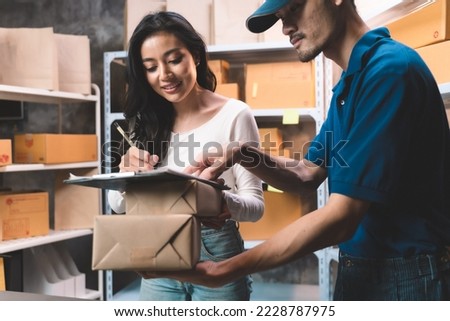 young woman sign for receive a parcel from delivery service man with shipment uniform. Young women with new business about online shopping in home office and small store.
