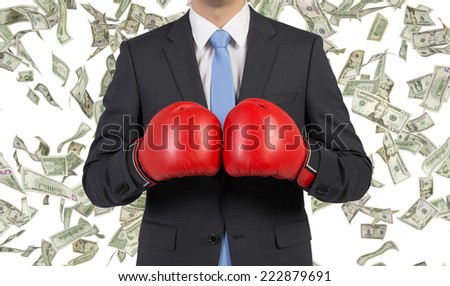 Businessman in boxing gloves, falling dollars background.