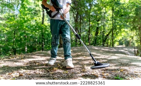a boy with a metal detector in the forest is looking for treasure. High quality photo