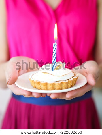 Lovely girl holding in hands cupcake with one candle. Happy holiday celebration, birthday party, fun and joy concept. Close up