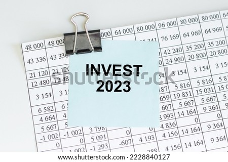 invest 2023 text on a card clip to a paper on a table