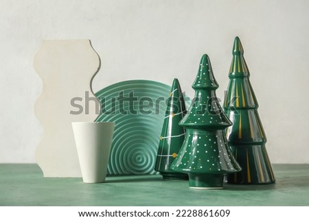 Decorative Christmas trees with podiums on table near light wall
