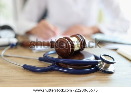 Close-up of judge hammer and doctor stethoscope on office desk. Medical malpractice, personal injury lawyer and healthcare legal aspects concept Royalty-Free Stock Photo #2228865575
