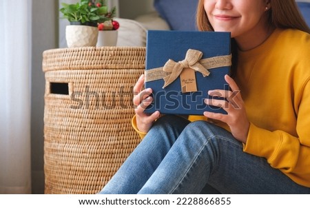 Closeup image of a young woman holding and receiving a present box at home
