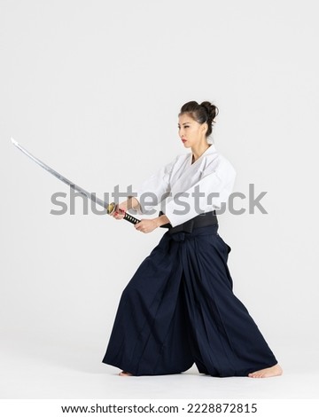 Aikido master woman in traditional samurai hakama kimono with black belt with sword, katana on white background. Healthy lifestyle and sports concept. Royalty-Free Stock Photo #2228872815
