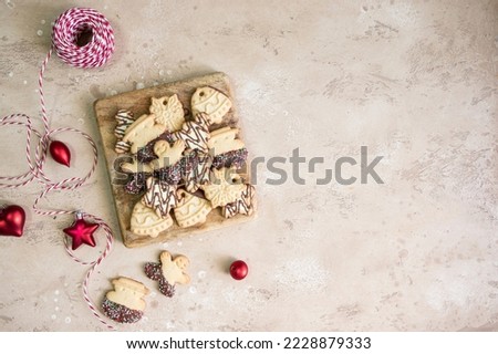 Top view of Christmas gingerbread cookies on wooden try beige background. Snowflake, star, man, bell, candy shapes.