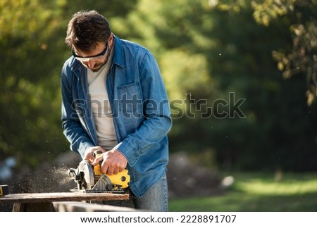 Craftsman working with circular saw at construction site Royalty-Free Stock Photo #2228891707