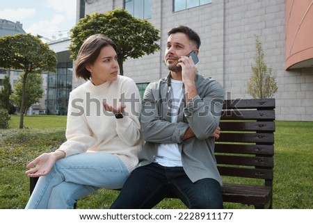 Man ignoring his girlfriend and talking on phone. Relationship problems Royalty-Free Stock Photo #2228911177