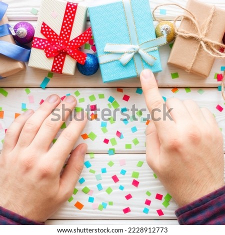 man chooses Christmas gift on a background of confetti