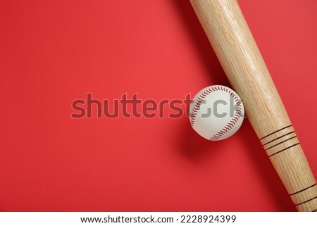 Wooden baseball bat and ball on red background, flat lay. Space for text