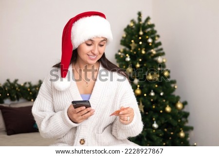 Merry Christmas. A beautiful young woman makes purchases on her smartphone via the Internet. Pay for online shopping. Lifestyle. High quality photo