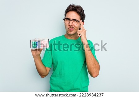 Young hispanic man holding battery box isolated on white background pointing temple with finger, thinking, focused on a task.