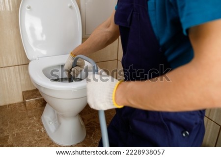 plumber unclogging blocked toilet with hydro jetting at home bathroom. sewer cleaning service Royalty-Free Stock Photo #2228938057