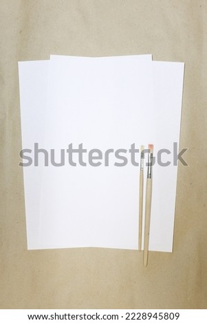 sheet of white paper and artistic brushes on crafting background