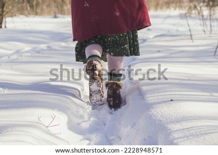 Close up throwing snow concept photo. Legs in winter footwear. Snowfall. Back view photography with snowdrifts on background. High quality picture for wallpaper, travel blog, magazine, article
