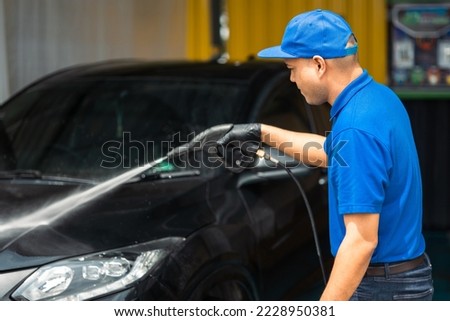 Man worker washing car service. Car wash cleaning station high pressure water. Employees clean a vehicle professionally. Royalty-Free Stock Photo #2228950381