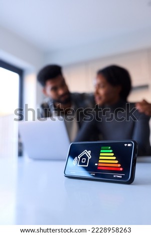 Worried Couple At Home Looking At Laptop With Smart Energy Meter In Foreground Royalty-Free Stock Photo #2228958263
