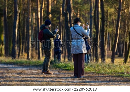 People taking photo of the autumn park with their phones