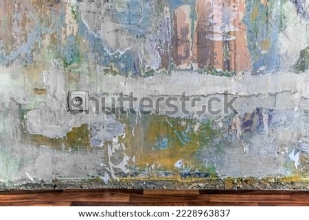 Vintage wall and floor mockup in a room with multi-colored paint stains, plaster, remnants of paper wallpaper and a European electrical outlet. Architectural template with copy space