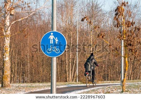 Back view of cyclist cycling on a bike path. Bicycle sign and bike rider. Winter season. Royalty-Free Stock Photo #2228967603
