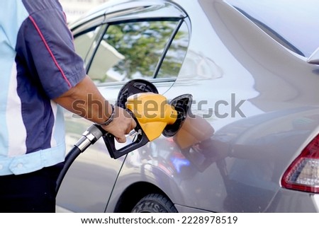 A man uses his hand to open a gasoline or diesel nozzle. To fill a car parked at a gas station with a gasoline or diesel dispenser. Royalty-Free Stock Photo #2228978519