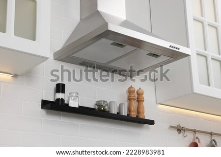 Modern range hood over shelf with spices in kitchen Royalty-Free Stock Photo #2228983981