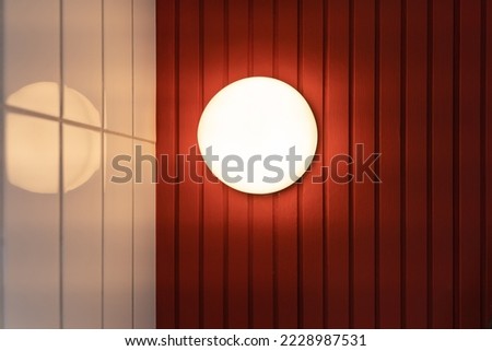 Beautiful modern round shape wall lamp light bulb decoration for home and living on the red and white wall background with copy space for text. Concept building interior contemporary.