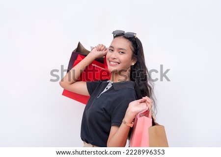 A lively asian woman holding shopping bags on both hands after going on a shopping spree. Getting satisfaction from buying. Isolated on a white background. Retail and sale concepts. Royalty-Free Stock Photo #2228996353