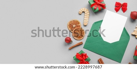 Envelope with blank greeting card, gifts and Christmas decor on grey background with space for text