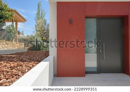 The front entrance of a new house, with a modern luxury door. The use of Wood chips is decorative on the site.