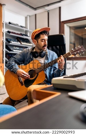 Stock photo of concentrated artist in music studio playing the guitar.