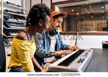 Stock photo of black woman playing electronic piano keyboard in music studio.