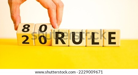 80 on 20 rule symbol. Pareto principle. Male hand flips wooden cubes with words '80 on 20 rule'. Beautiful yellow table, white background, copy space. Business and 80 on 20 rule, pareto concept. Royalty-Free Stock Photo #2229009671