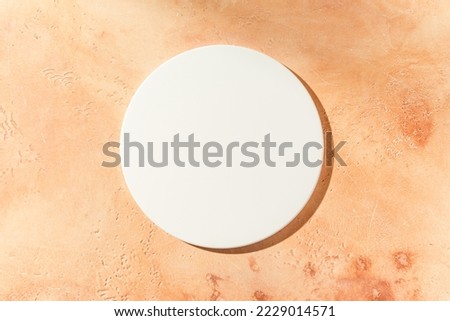 Empty white circle mockup podium for product presentation on a sandy textured background with hard light. Trendy design flat lay with copy space. Top view.