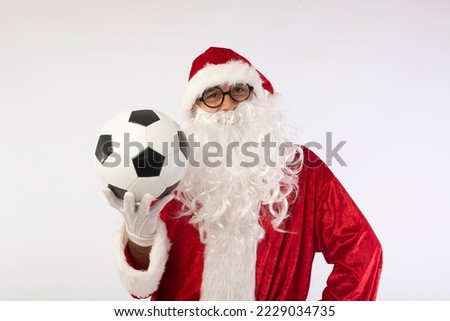 Santa Claus with glasses holding a World Cup soccer ball as a gift for all children, with a white background where his red suit and white beard stand out Royalty-Free Stock Photo #2229034735