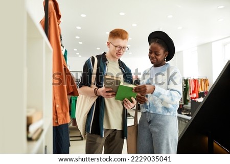 Waist up portrait of gen Z young people looking at used books in thrifting shop or swap event Royalty-Free Stock Photo #2229035041