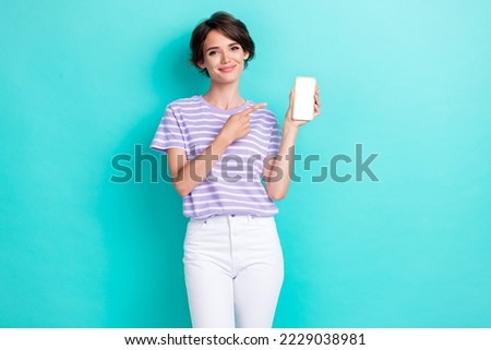 Photo of sweet pretty lady wear violet t-shirt pointing finger modern gadget empty space isolated turquoise color background