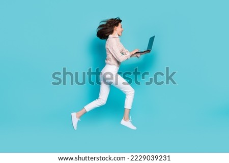 Side profile photo of excited crazy woman jumping air trampoline hurry done her homework education deadline hold laptop isolated on blue color background