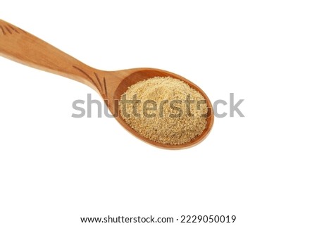 Hulbah powder or Fenugreek flour in wooden spoon isolated on white background, close-up, selective focus. Herbal nutritional supplement. Soothe upset stomach and digestive problems.