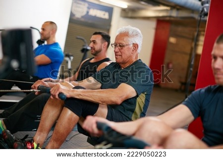 Still keeping pace with the youngsters. Cropped shot of a group of men working out on the rowing machine at the gym. Royalty-Free Stock Photo #2229050223