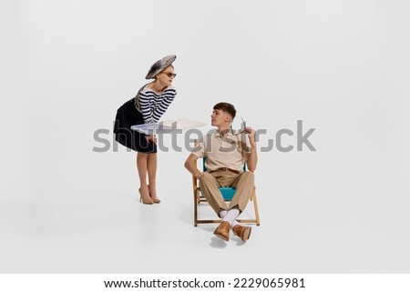 Portrait of young man travelling on cruise, resting. Woman in striped shirt serving isolated on white background. Concept of summer holiday, occupation, retro fashion, vintage style. Copy space for ad