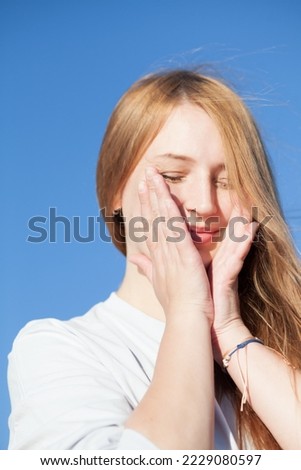 Close-up photo of amazing happy girl with pale skin shy laughing and cover face with hand.