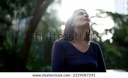 Thoughtful woman standing outside looking at sky in contemplation. Pensive person lost in thought Royalty-Free Stock Photo #2229087241