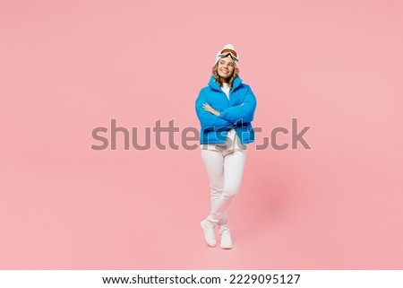 Snowboarder happy woman wear blue suit goggles mask hat ski padded jacket stand look aside on workspace isolated on plain pastel pink background. Winter extreme sport hobby weekend trip relax concept