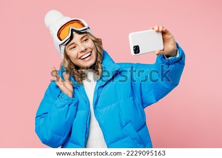 Snowboarder woman wear blue suit goggles mask hat ski padded jacket do selfie shot on mobile cell phone isolated on plain pastel pink background. Winter extreme sport hobby weekend trip relax concept