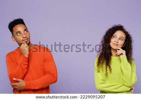 Young minded thoughtful couple two friends family man woman of African American ethnicity wear casual clothes together prop up chin look aside on area isolated on pastel plain light purple background