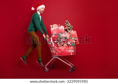 Full size photo of overjoyed excited person jumping pushcart pile stack giftbox isolated on red color background